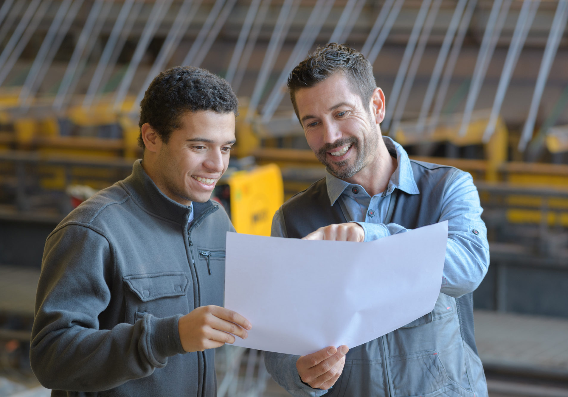 male supervisor with worker discussing over blueprints in industry